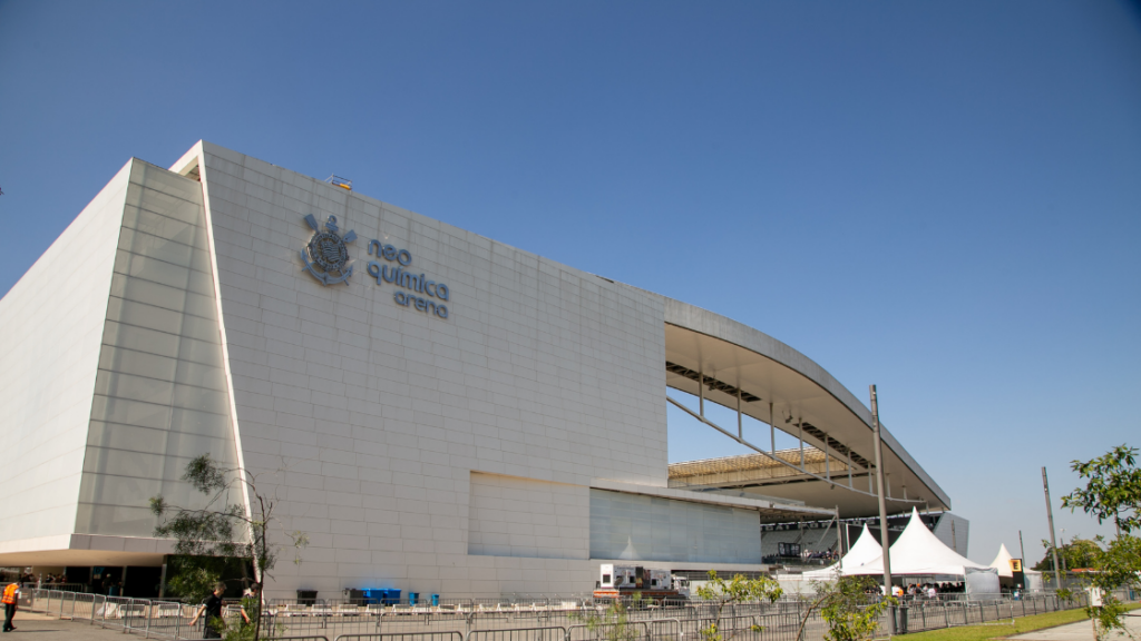 Fachada da Neo Química Arena, onde é possível enxergar o nome do local na lateral do prédio, sob um céu azul